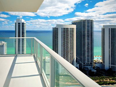 alt="Oceanfront view from a condo balcony links to search condos in for sale in South Florida."